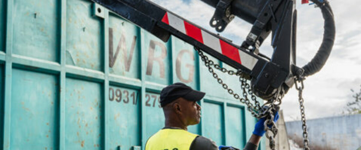 Mitarbeiter steuert einen Kran zur Containerbeladung