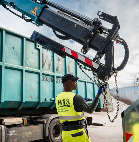 Mitarbeiter steuert einen Kran zur Containerbeladung